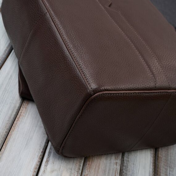 Detail lícovej hnedej kože a prešívania na elegantnom pánskom batohu