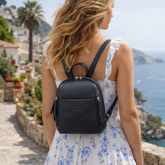 Mladá žena v meste s elegantným čiernym koženým batohom a malou crossbody kabelkou