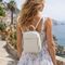 Elegatná žena s béžovým koženým batohom a malou crossbody kabelkou v meste